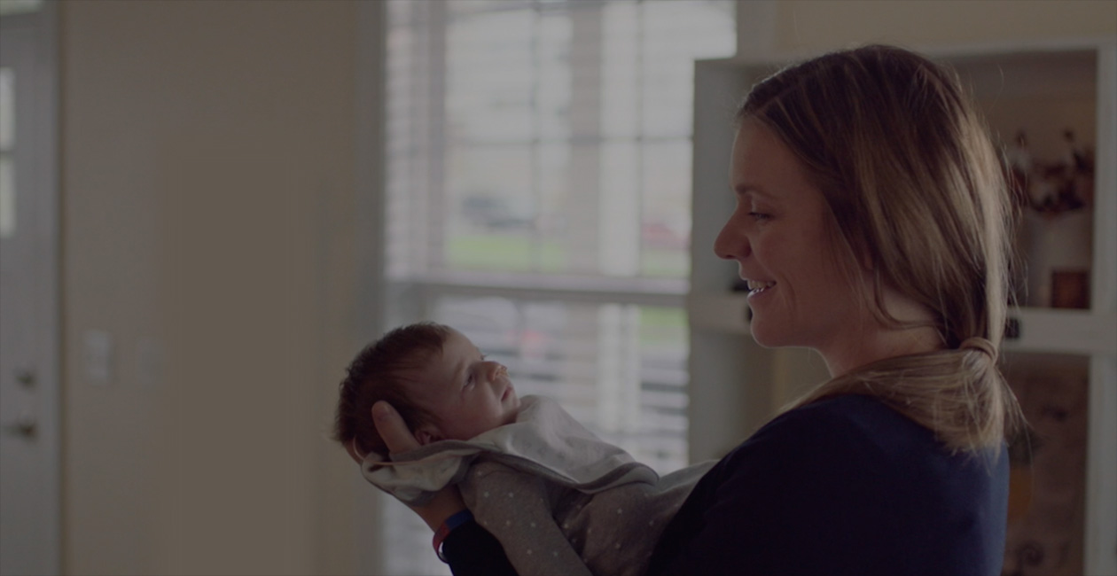 Uma mãe sorrindo para seu novo bebê.