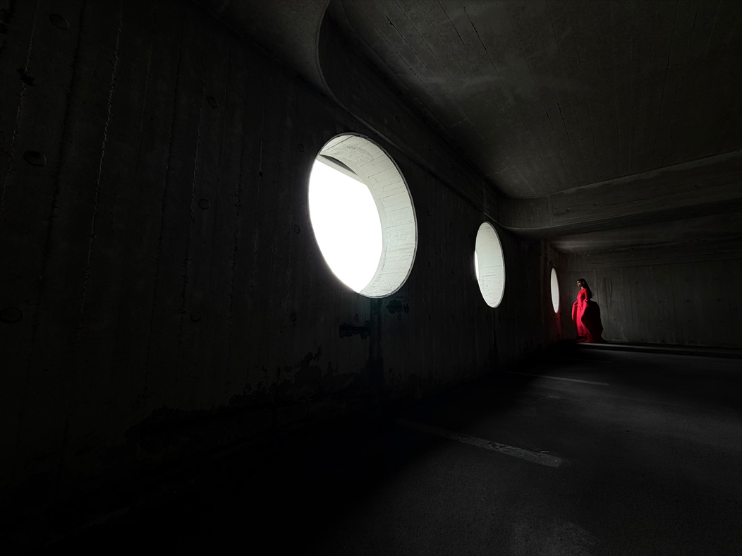 一位女士身穿紅色長裙，站在空房間內拍照留影；相機 app 的焦距切換至 13 毫米，以展示 Pro 相機系統的功能