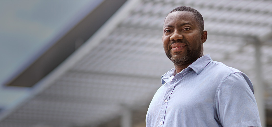 Kofi seisoo ulkona ja hymyilee kameraan.