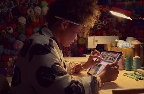En person sitter ved et skrivebord og bruker to fingre til å zoome inn på en iPad-skjerm.