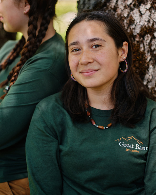 Nicole Long tiene puesta una camiseta del Great Basin Institute y posa frente a un árbol.