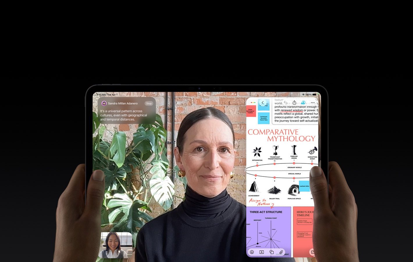Vista frontal do iPad Pro, preto sideral, mãos a segurar os lados esquerdo e direito do dispositivo na horizontal, ecrã com moldura preta e cantos arredondados, o ecrã apresenta uma conversa no FaceTime com tradução em tempo real e uma app educativa com uma apresentação intitulada "Mitologia Comparativa" com texto, diagramas e notas escritas à mão