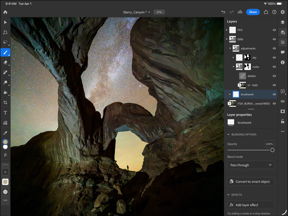 Vista frontal do iPad Pro, preto sideral, colocado na horizontal, ecrã com moldura preta e cantos arredondados, a mostrar a edição de uma fotografia de um desfiladeiro e do céu noturno coberto de estrelas, no lado direito, são visíveis as camadas, ferramentas e efeitos de edição, incluindo pinceladas, ajustes e outros