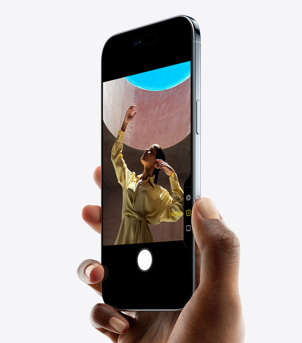 一隻手握著 iPhone Air,拇指按著相機控制按鈕,機身正側面展示纖薄外形、動態島、側邊按鈕