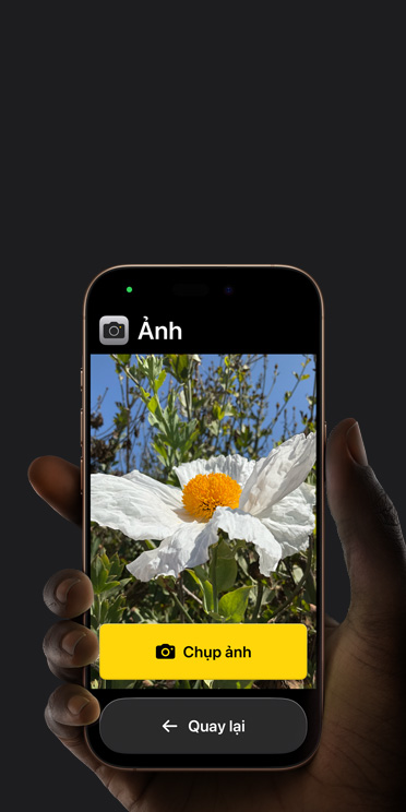 Màn hình iPhone 16e hiển thị giao diện ứng dụng Camera giản lược với bông hoa trắng trong khung hình, nút “Chụp ảnh” và nút “Quay lại” bên dưới